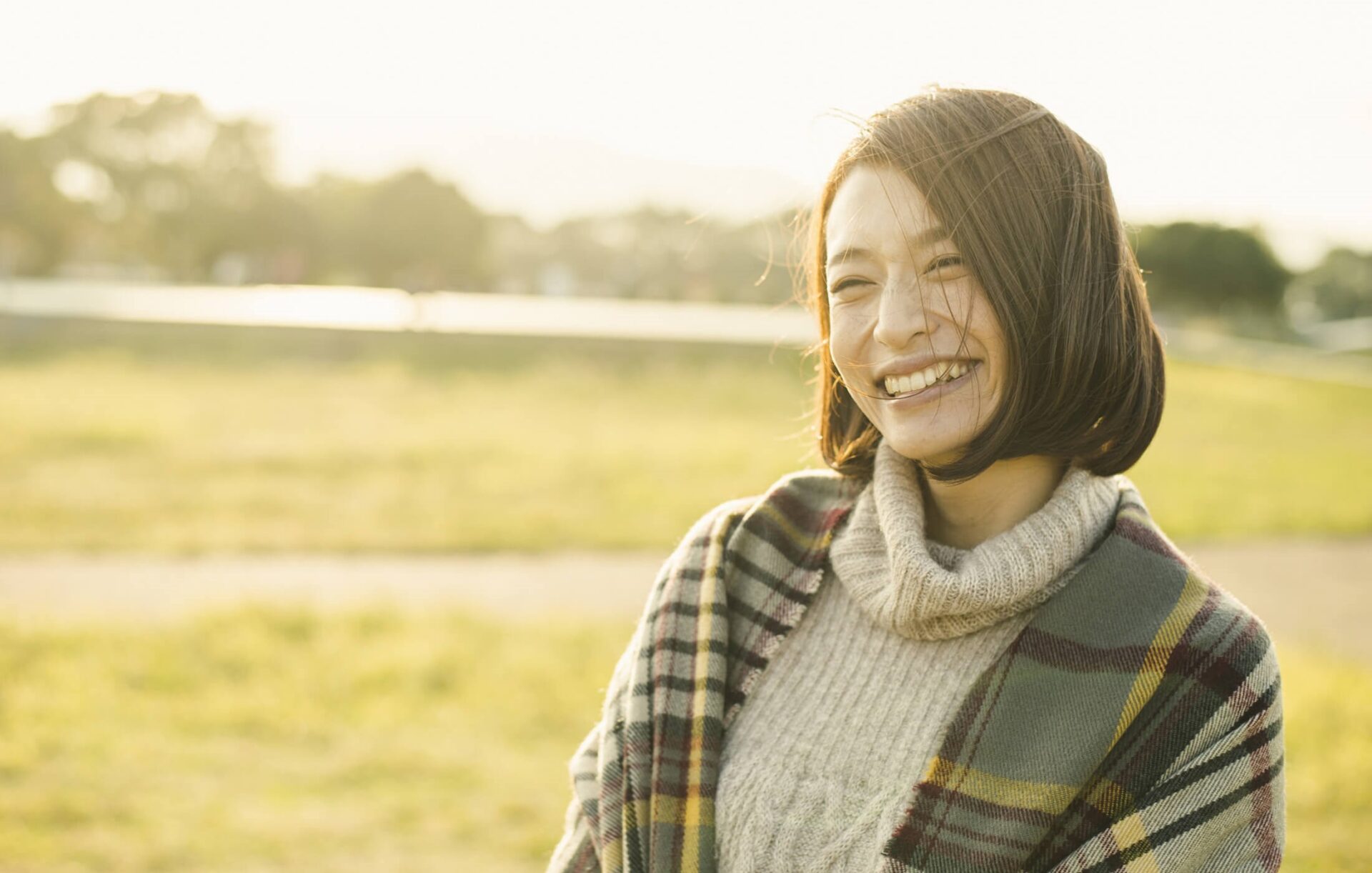 A woman in sweater and scarf smiling for the camera.